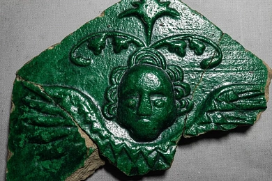 Фрагмент паліванай кафлі-каронкі з галоўкай херувіма з Навагрудка