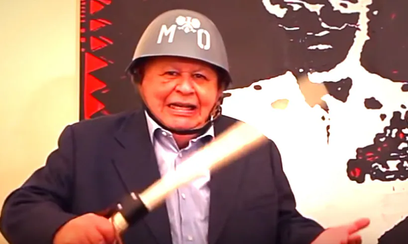 Ежы Урбан бадзёра пазуе у міліцэйскай касцы і з дручком часоў вайсковага стану.jpg