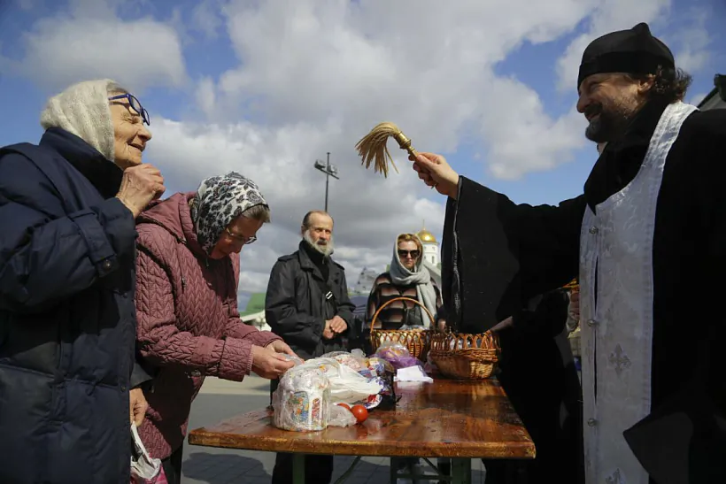 Pravaslaŭny sviatar asviačaje tradycyjnyja vielikodnyja bulki i farbavanyja jajki kalia carkvy ŭ Miensku Pravaslaŭny sviatar asviačaje tradycyjnyja vielikodnyja bulki i farbavanyja jajki kalia carkvy ŭ Miensku